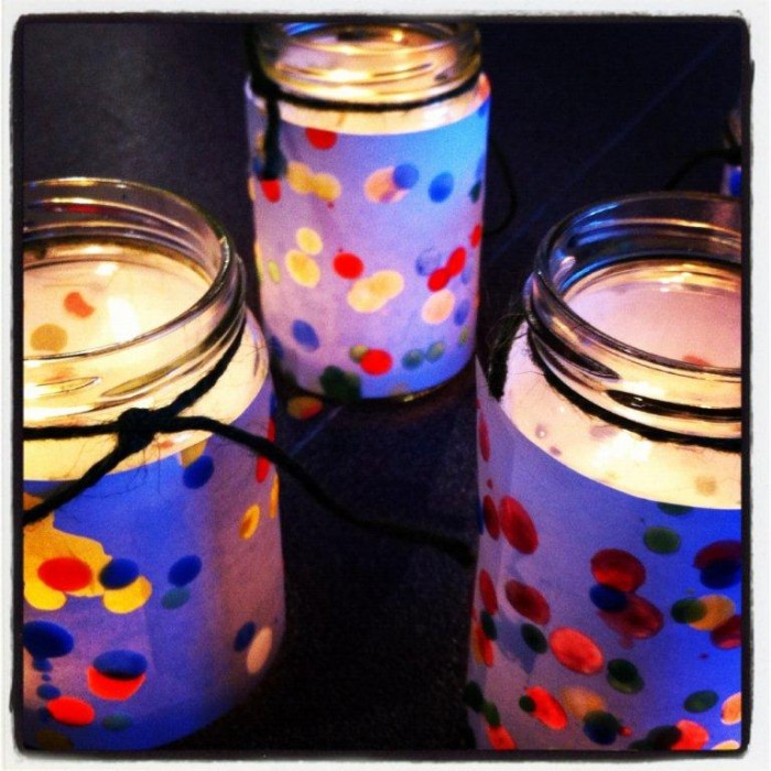 Image of jars with candles lit inside. Colored paper wrap surrounds jars.