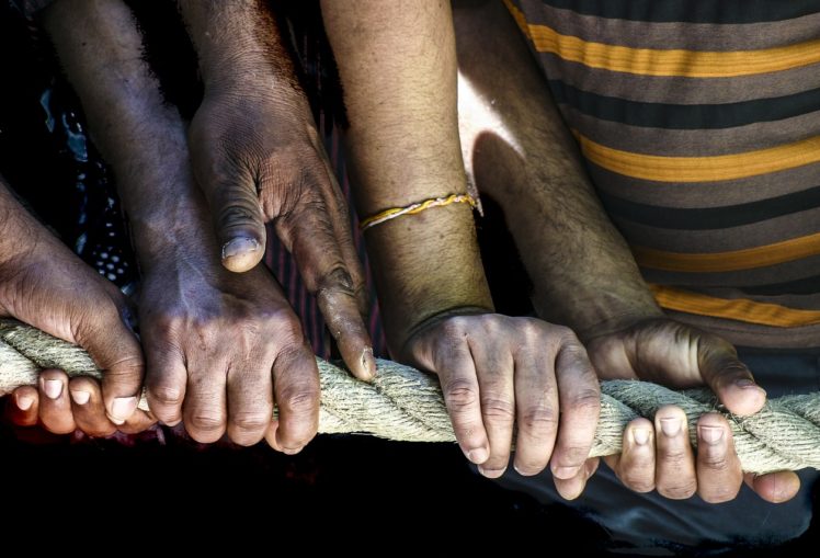 Close up photo of arms holding a rope together