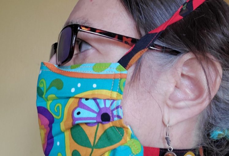 Profile of individual wearing a colorful fabric mask covering the mouth and nose.